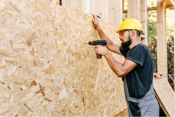 Construction worker installing external wall insulation grant-eligible materials on residential building