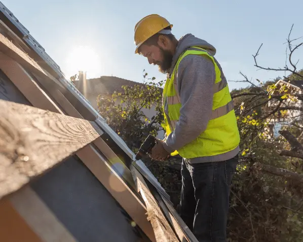 Worker installing flat roof insulation grants-eligible materials on residential property roof