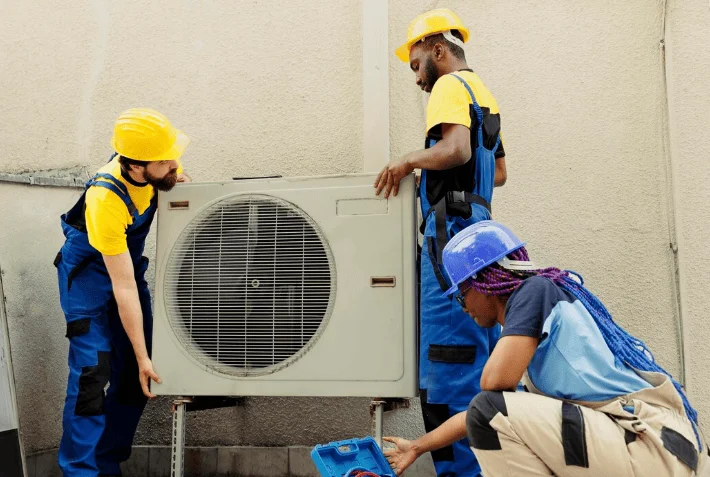 Professional technicians installing air source heat pump grant eligible system on exterior wall
