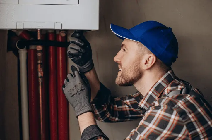 Heating engineer inspecting boiler pipes for Free Boiler Grant eligibility assessment